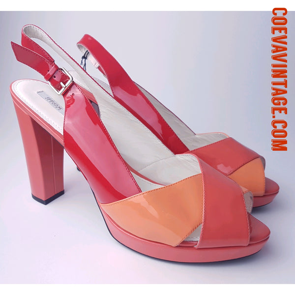 Closeup Three-quarter view of unworn Geox Respira colour-block platform sandals in red, coral and peach, with crossover peep toes, block heels and buckled slingback straps.