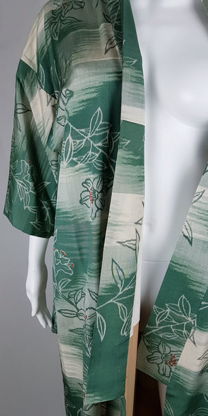 Detailed side view of the wide sleeve and long front panel on a vintage green and cream floral silk kimono.