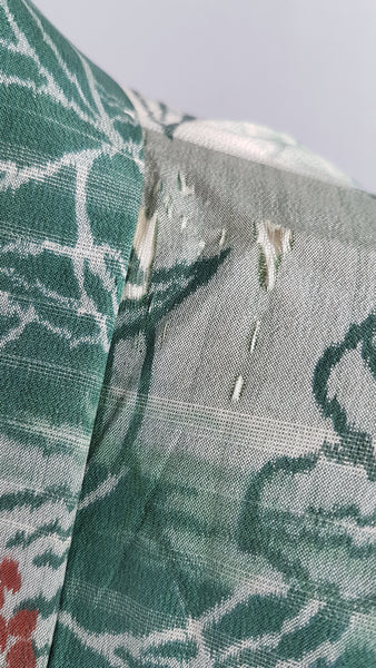 Condition close-up showing several small moth nibbles and areas of surface loss near the right side of the kimono neckline.