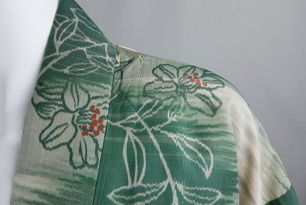 Close-up of the right shoulder showing the ivory floral motif and small moth nibbles near the collar seam.