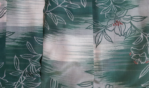 Detailed view of the green, sage and ivory floral silk showing the abstract brushstroke bands and faint scattered discolouration.