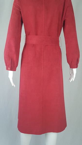 Vintage 1970's Halston Ultra Suede red knee length wrap coat dress with long sleeves, a wide collar, and a matching tie belt on a mannequin 