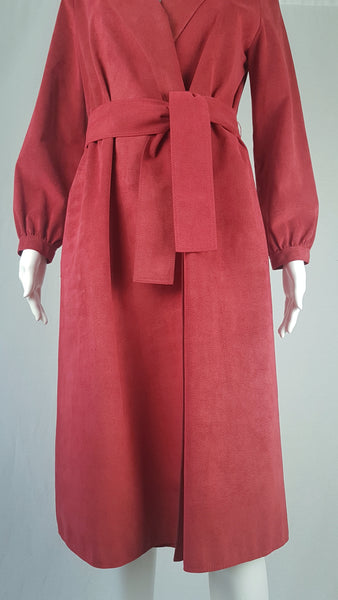 Vintage 1970's Halston Ultra Suede red knee length wrap coat dress with long sleeves, a wide collar, and a matching tie belt on a mannequin 