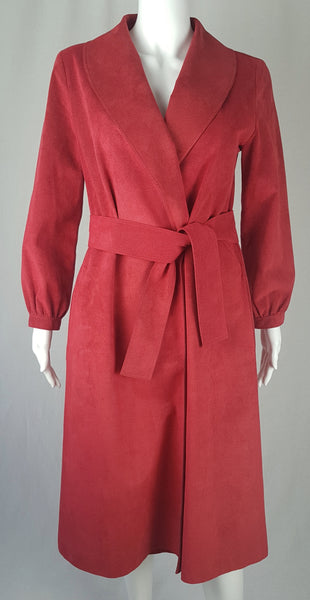 Vintage 1970's Halston Ultra Suede red knee length wrap coat dress with long sleeves, a wide collar, and a matching tie belt on a mannequin 