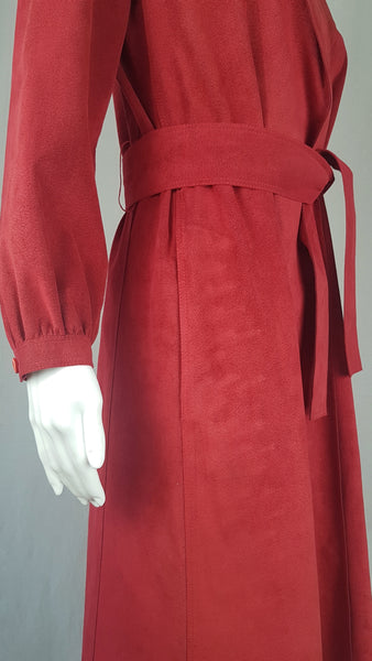 Vintage 1970's Halston Ultra Suede red knee length wrap coat dress with long sleeves, a wide collar, and a matching tie belt on a mannequin 