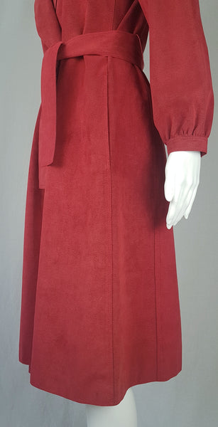 Sleeve and botton part of garment view on Vintage 1970's Halston Ultra Suede red knee length wrap coat dress with long sleeves, a wide collar, and a matching tie belt on a mannequin 