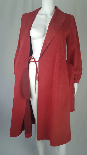 Vintage 1970's Halston Ultra Suede red knee length wrap coat dress with long sleeves, a wide collar, and a matching tie belt on a mannequin 
