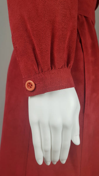 Sleeve button view on Vintage 1970's Halston Ultra Suede red knee length wrap coat dress with long sleeves, a wide collar, and a matching tie belt on a mannequin 