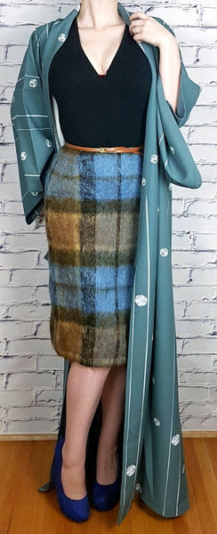 Woman modelling a blue grey kimono robe with wide sleeves, white stripes and floral medallions, styled over a black top and plaid skirt - front view