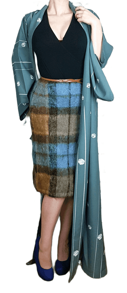 Woman modelling a blue grey kimono robe with wide sleeves, white stripes and floral medallions, styled over a black top and plaid skirt.