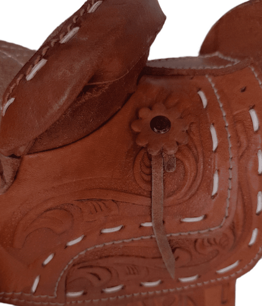Close-up of a vintage Mexican tooled-leather saddle purse with a leather rosette concho, suede saddle strings and horse-head tooling.