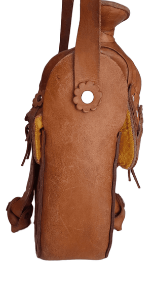 Side view close-up of a vintage Mexican tooled-leather saddle purse with a leather rosette concho, suede saddle strings and horse-head tooling.