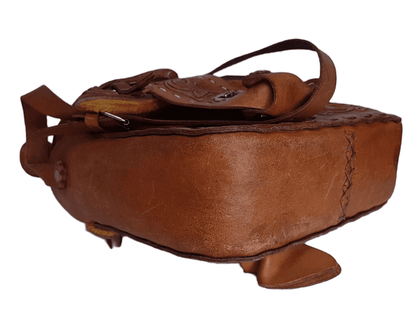 Bottom three-quarter view of a vintage 1960s Mexican tooled-leather crossbody bag constructed as a miniature Western horse saddle.