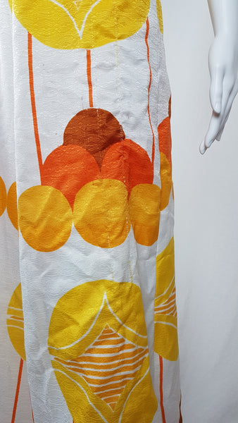 Vintage 1960s white palazzo jumpsuit on a mannequin with a V-neck and bold orange and yellow abstract print - fabric and print details