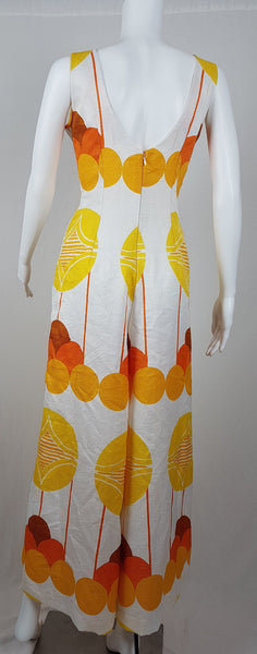 Vintage 1960s white palazzo jumpsuit on a mannequin with a V-neck and bold orange and yellow abstract print - back view