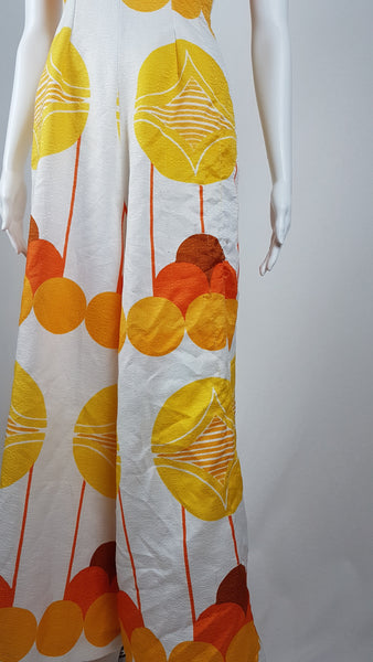 Vintage 1960s white palazzo jumpsuit on a mannequin with a V-neck and bold orange and yellow abstract print - pant details