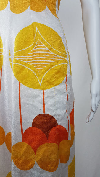 Vintage 1960s white palazzo jumpsuit on a mannequin with a V-neck and bold orange and yellow abstract print - fabric and print details
