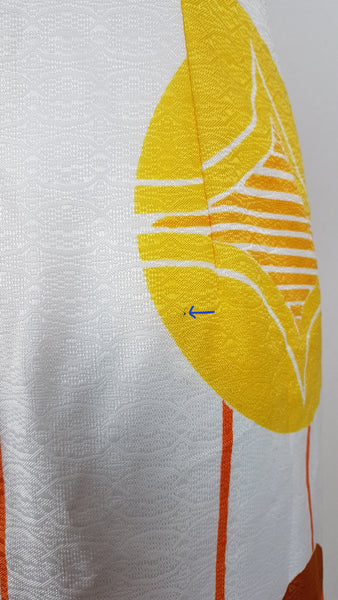 Blue arrow pointing to flaw - Vintage 1960s white palazzo jumpsuit on a mannequin with a V-neck and bold orange and yellow abstract print - fabric and print details