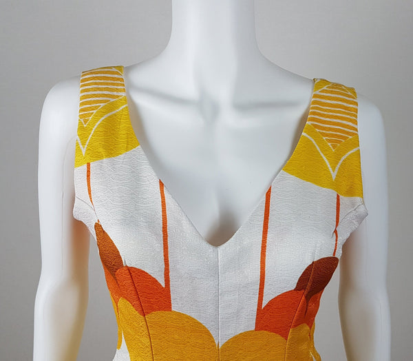 Vintage 1960s white palazzo jumpsuit on a mannequin with a V-neck and bold orange and yellow abstract print - shoulder and bust view