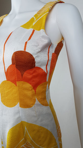 Vintage 1960s white palazzo jumpsuit on a mannequin with a V-neck and bold orange and yellow abstract print - shoulder and bust side view