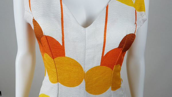 Vintage 1960s white palazzo jumpsuit on a mannequin with a V-neck and bold orange and yellow abstract print - shoulder and bust view