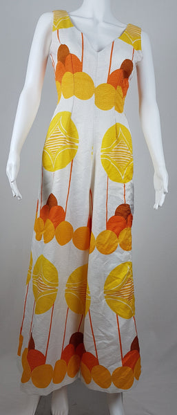 Vintage 1960s white palazzo jumpsuit on a mannequin with a V-neck and bold orange and yellow abstract print - back view