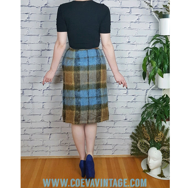 Woman wearing a black v-neck short sleeve top, and a Vintage 1970s Andrew Stewart mohair and wool pencil skirt with a fuzzy plaid pattern in blue, brown, grey, and olive 