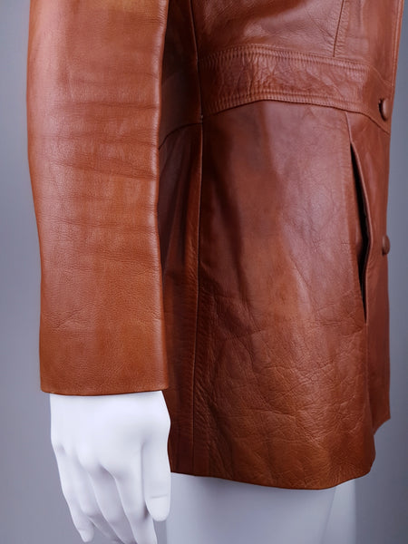 Side view showing the long fitted sleeve, vertical welt pocket and warm tonal variation in the cognac leather