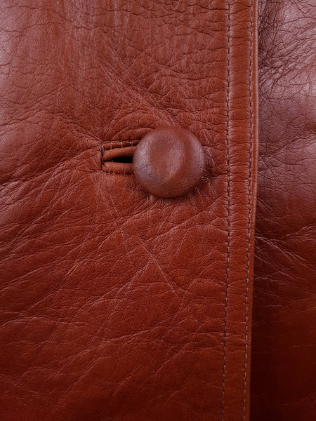 Leather-covered front button and bound buttonhole against the naturally grained cognac leather