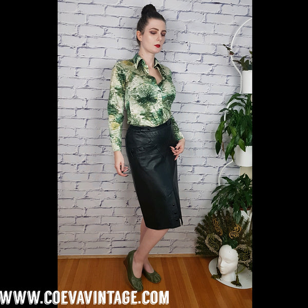 Vintage 1970s fitted long sleeve shirt with a pointed collar and green forest landscape print modelled by a woman wearing a black knee length leather skirt - front view