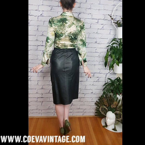 Vintage 1970s fitted long sleeve shirt with a pointed collar and green forest landscape print modelled by a woman wearing a black knee length leather skirt - back view