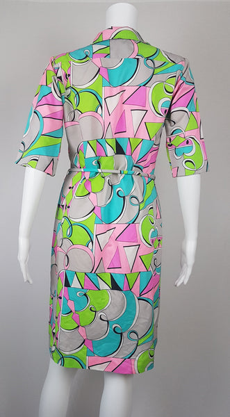 Back view of Front view of Vintage 1980s Lady Bayard shirt dress with short sleeves, a pointed collar, button front, matching tie belt, and a bold abstract geometric print in pink, turquoise, lime green, grey, and black displayed on a mannequin