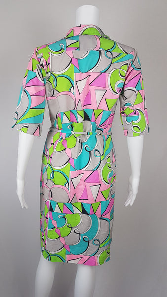 Back view of Front view of Vintage 1980s Lady Bayard shirt dress with short sleeves, a pointed collar, button front, matching tie belt, and a bold abstract geometric print in pink, turquoise, lime green, grey, and black displayed on a mannequin