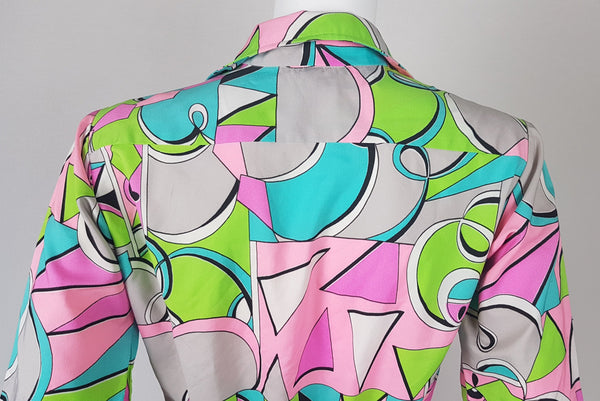 Back shoulder view of Front view of Vintage 1980s Lady Bayard shirt dress with short sleeves, a pointed collar, button front, matching tie belt, and a bold abstract geometric print in pink, turquoise, lime green, grey, and black displayed on a mannequin