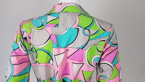 Back shoulder view of Front view of Vintage 1980s Lady Bayard shirt dress with short sleeves, a pointed collar, button front, matching tie belt, and a bold abstract geometric print in pink, turquoise, lime green, grey, and black displayed on a mannequin