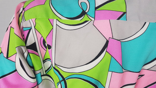 Closeup of fabric print on Vintage 1980s Lady Bayard shirt dress with short sleeves, a pointed collar, button front, matching tie belt, and a bold abstract geometric print in pink, turquoise, lime green, grey, and black displayed on a mannequin