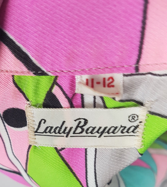 Label of Back shoulder view of Front view of Vintage 1980s Lady Bayard shirt dress with short sleeves, a pointed collar, button front, matching tie belt, and a bold abstract geometric print in pink, turquoise, lime green, grey, and black displayed on a mannequin