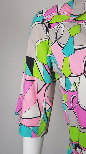 Closeup of sleeve view on Front view of Vintage 1980s Lady Bayard shirt dress with short sleeves, a pointed collar, button front, matching tie belt, and a bold abstract geometric print in pink, turquoise, lime green, grey, and black displayed on a mannequin