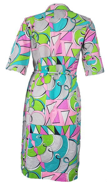 Back view of Vintage 1980s Lady Bayard shirt dress with short sleeves, a pointed collar, button front, matching tie belt, and a bold abstract geometric print in pink, turquoise, lime green, grey, and black displayed on a mannequin
