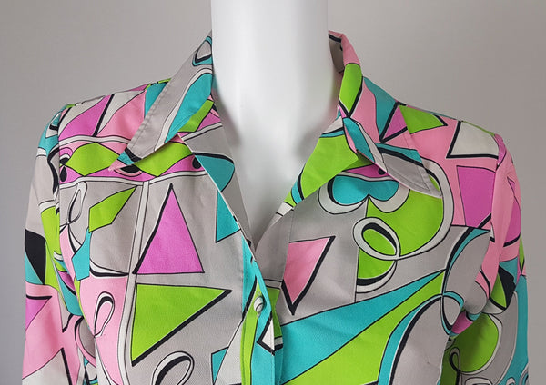 Front view of shoulder and collar of Front view of Vintage 1980s Lady Bayard shirt dress with short sleeves, a pointed collar, button front, matching tie belt, and a bold abstract geometric print in pink, turquoise, lime green, grey, and black displayed on a mannequin