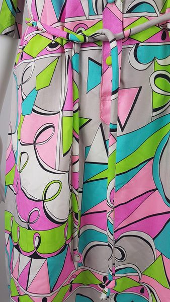 Closeup of tie belt on Front view of Vintage 1980s Lady Bayard shirt dress with short sleeves, a pointed collar, button front, matching tie belt, and a bold abstract geometric print in pink, turquoise, lime green, grey, and black displayed on a mannequin