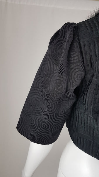 Vintage black brocade cropped bolero jacket with a fur collar, red satin lining, ribbon loop and decorative button displayed on a mannequin - back sleeve view