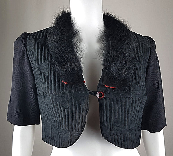 Vintage black brocade cropped bolero jacket with a fur collar, red satin lining, ribbon loop and decorative button displayed on a mannequin - front view