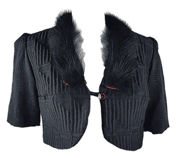 Vintage black brocade cropped bolero jacket with a fur collar, red satin lining, ribbon loop and decorative button displayed on a mannequin - front view