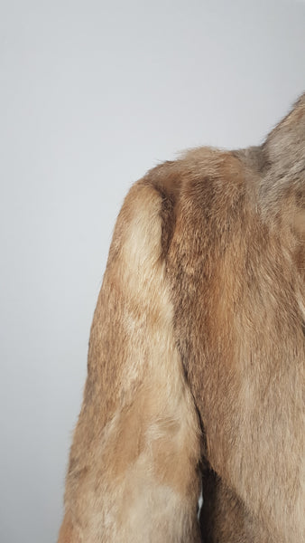 Close up of Vintage late 1980s to early 1990s brown rabbit fur jacket on a mannequin, showing the small area of fur loss or thinning at one shoulder, which is subtle and not immediately noticeable when worn. The wear may be consistent with friction from a shoulder bag, although the cause cannot be confirmed - back view