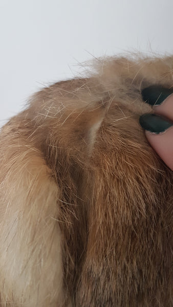 Close up of Vintage late 1980s to early 1990s brown rabbit fur jacket on a mannequin, showing the small area of fur loss or thinning at one shoulder, which is subtle and not immediately noticeable when worn. The wear may be consistent with friction from a shoulder bag, although the cause cannot be confirmed - back view