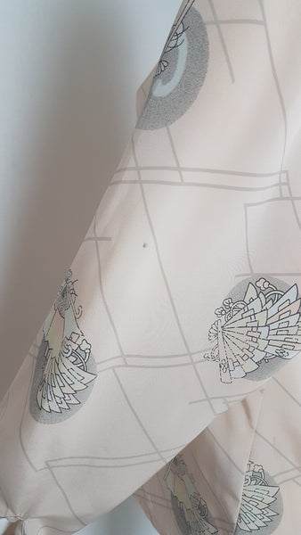 Sleeve of Vintage 1980s pastel peach Jac Dale shirt with long sleeves, a pointed collar, and an abstract grey fan print on a mannequin