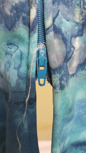 Zipper view of Vintage 1970s Missy House of Canada maxi dress with an aqua blue patterned bodice, long sleeves, pointed collar, and a white skirt with coordinating abstract panels shown on a mannequin